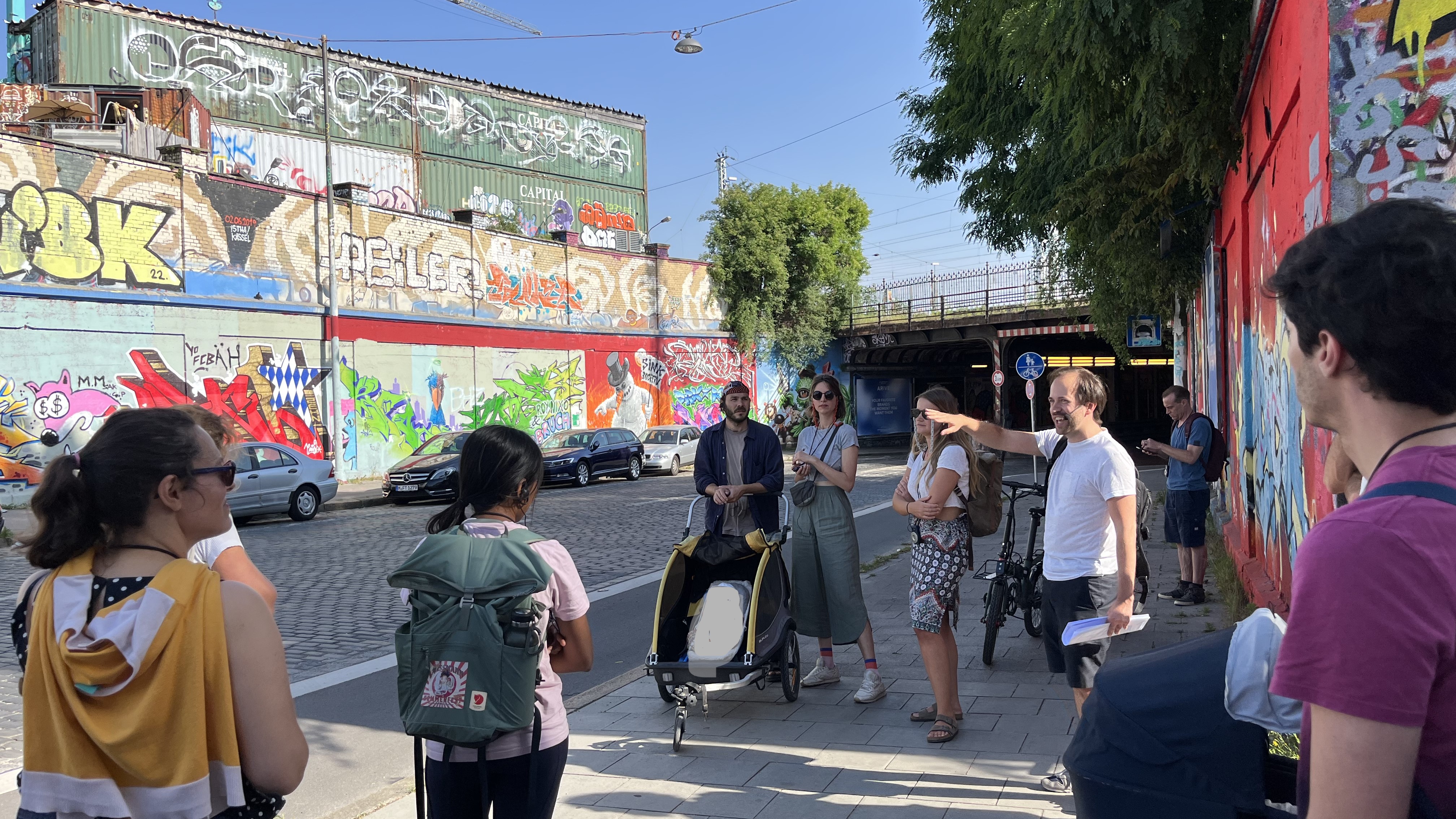 People standing opposite a graffiti wall. 